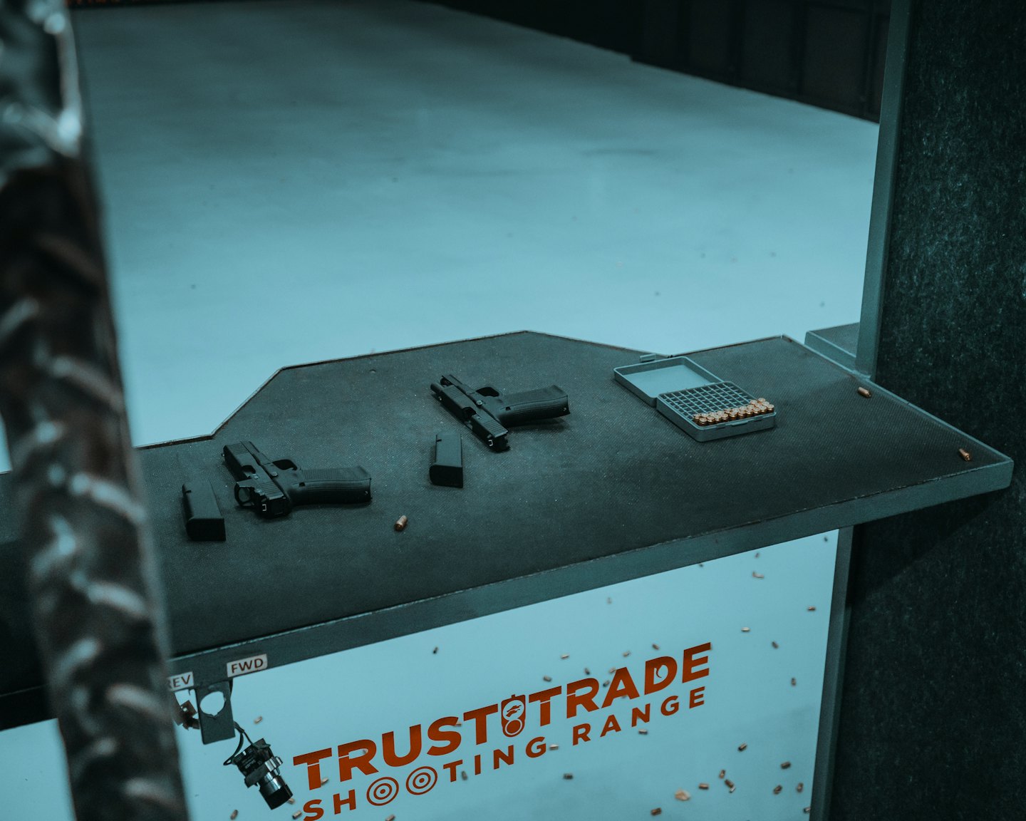 Two handguns, magazines, and ammunition sit on a shooting range table.