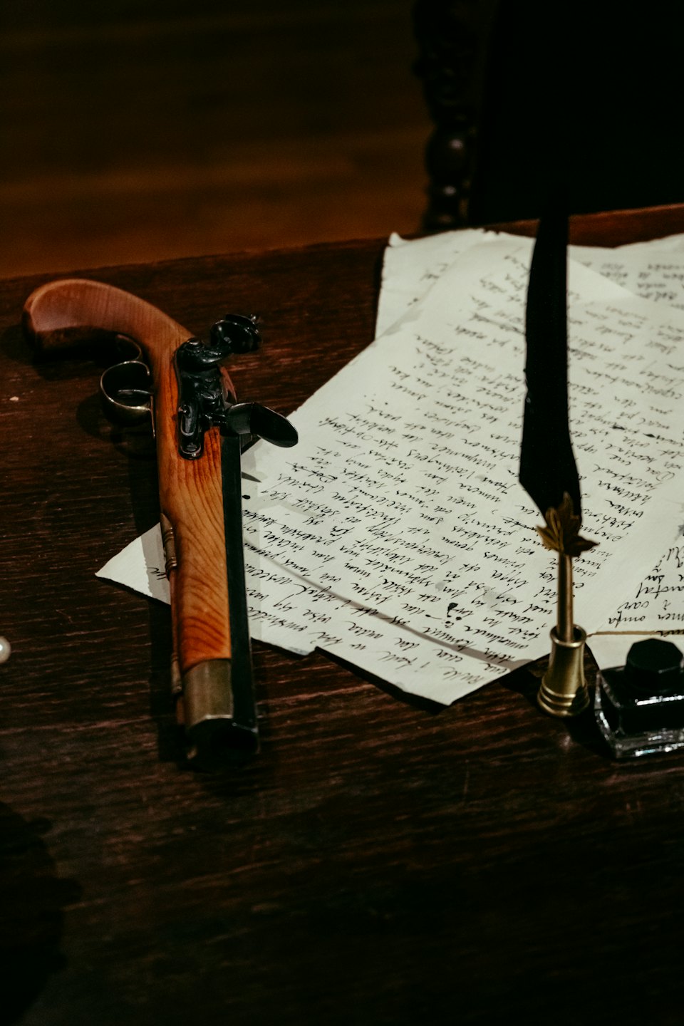 A vintage flintlock pistol rests on a desk beside historical documents.