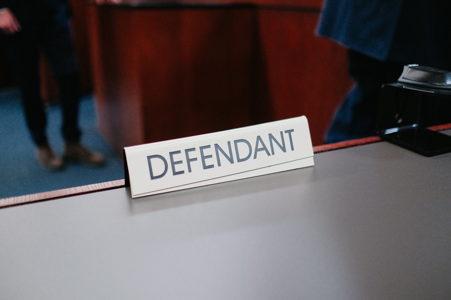 Defendant nameplate on a desk in a courtroom.